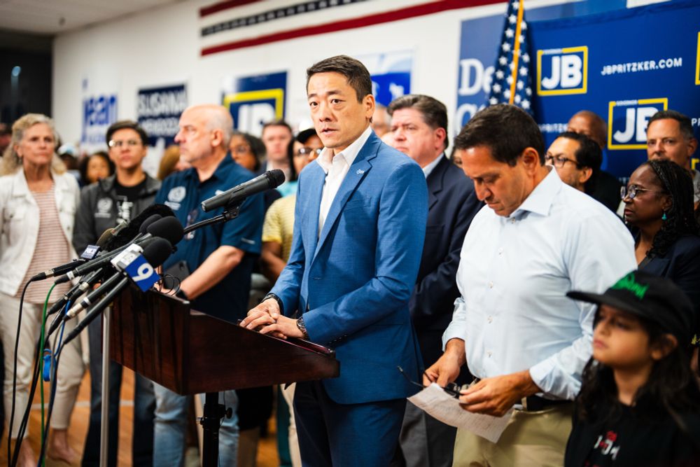 House Majority Leader Gene Wu speaks at a press conference. Several legislators, and Illinois Governor JB Pritzker, stand behind him.