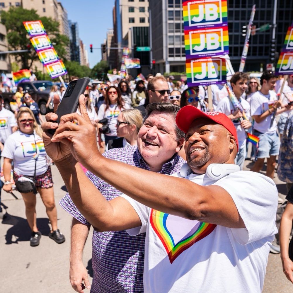Governor Pritzker takes a selfie with a person during a Pride Parade. 