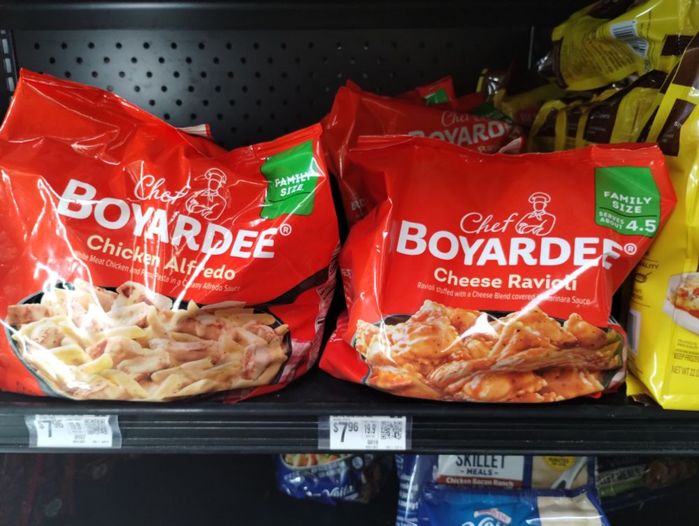 Two bags of frozen "Chef Boyardee" brand pasta cook at home kits. Both bags are primarily red with white lettering for the brand and flavor. The design is more elegant than the traditional design found on canned Chef Boyardee. The two flavors are Chicken Alfredo and Cheese Ravioli.