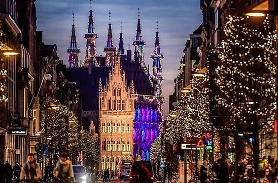 Nighttime view of Leuven city center decorated with Christmas lights, with historic buildings and streets glowing in a wintery atmosphere.

