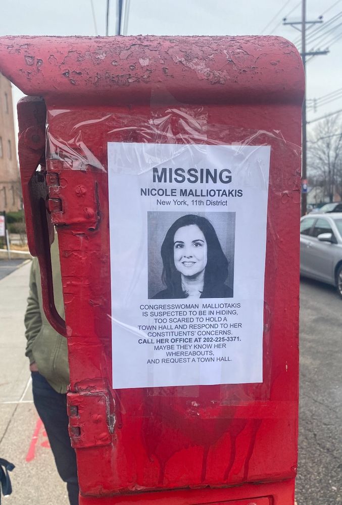 A flyer of a missing persons sign on a red street box with a photo of Nicole Malliotakis and text:

“Suspected to be in hiding, too scared to hold a town hall and respond to her constituents concerns. Call her office at 202-225-3371 maybe they know her whereabouts and request a town hall”