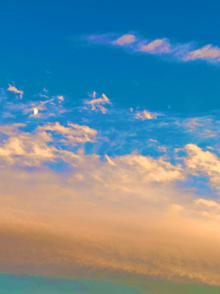 Photograph of the sky depicting graduating colour of sea green, soft sea foam like clouds rising into a bright blue abyss