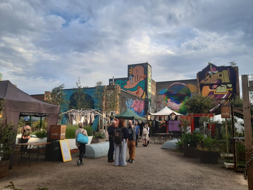 one angle of the site, featuring some attendees talking, and some of the murals done by the Brink group, who are artists and community activists 