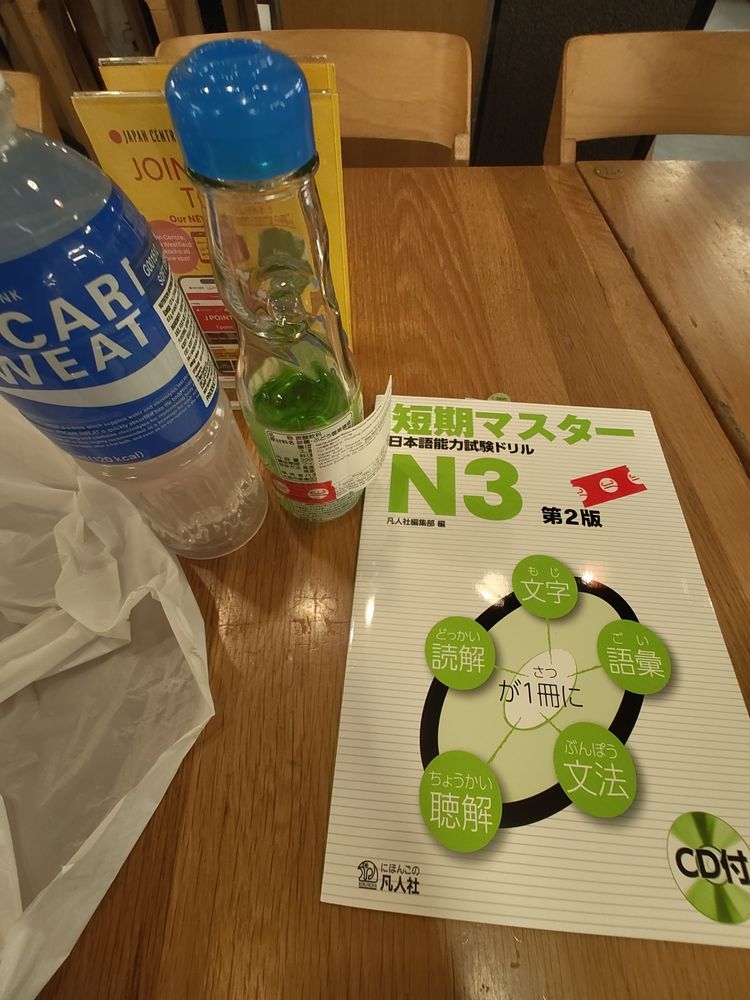 A bottle of pocari, ramune, and a Japanese textbook for N3