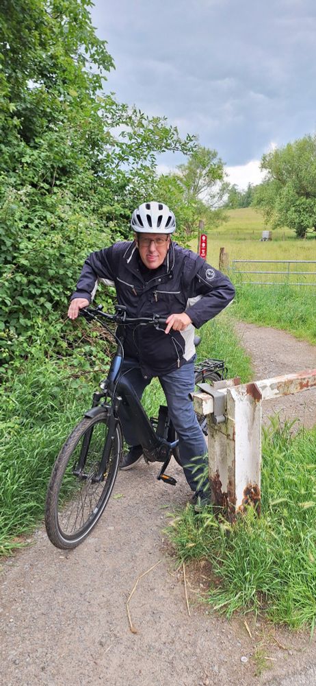Ralf Sandfuchs kämpft sich mit dem Fahrrad durch eine Absperrung am Ende eines Wanderweges.