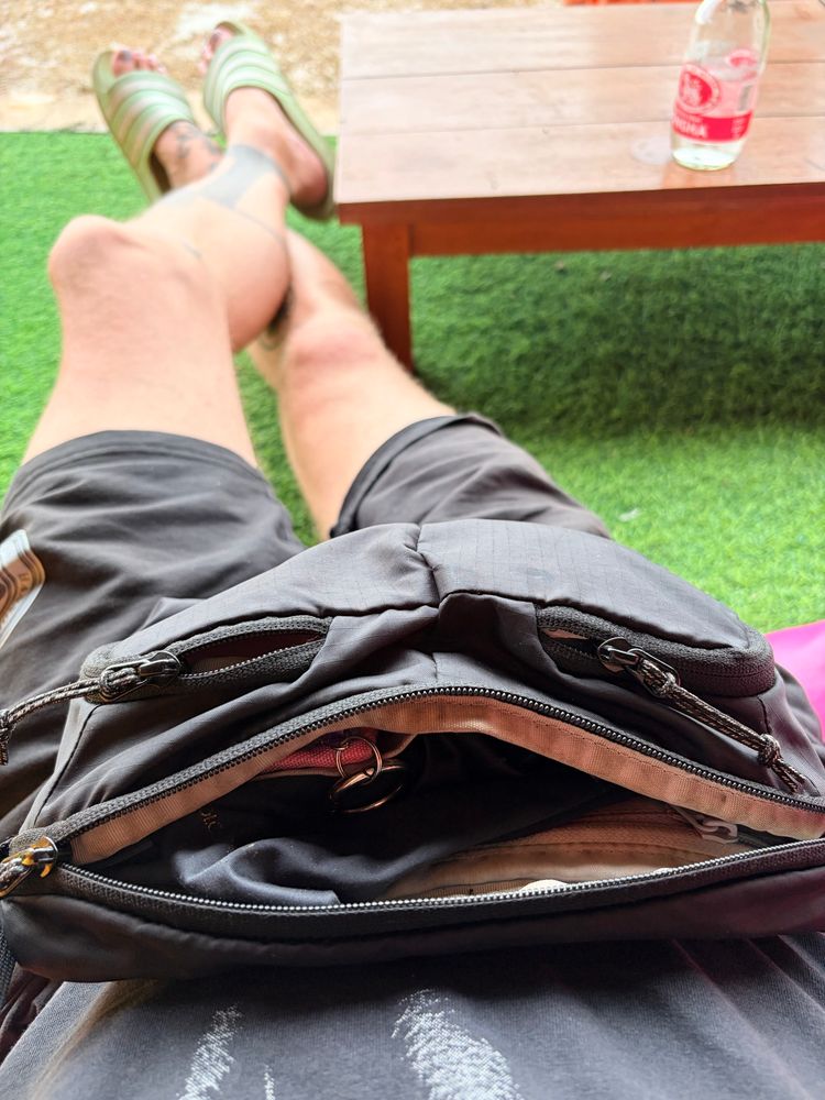 Eine Tasche liegt geöffnet auf ausgestreckten Beinen. Blick pov. Die Tasche sieht von oben aus wie das Gesicht von jabba the hut aus Star Wars 