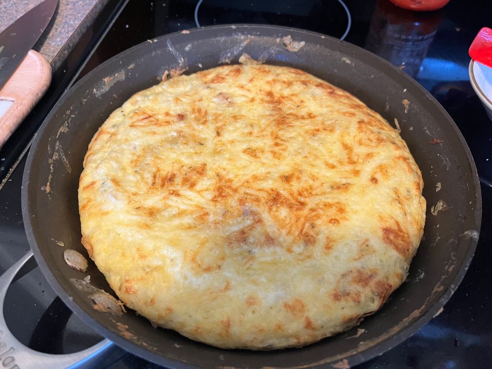Egg frittata in frying pan topped with toasted cheese 