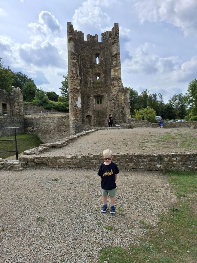 Small boy stood in foreground with castle ruins behind him