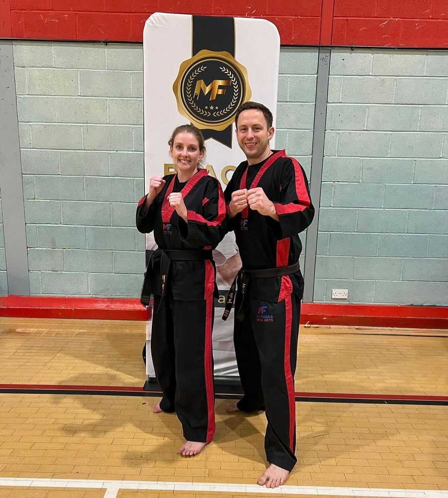 A young couple in martial arts attire posing for the camera 