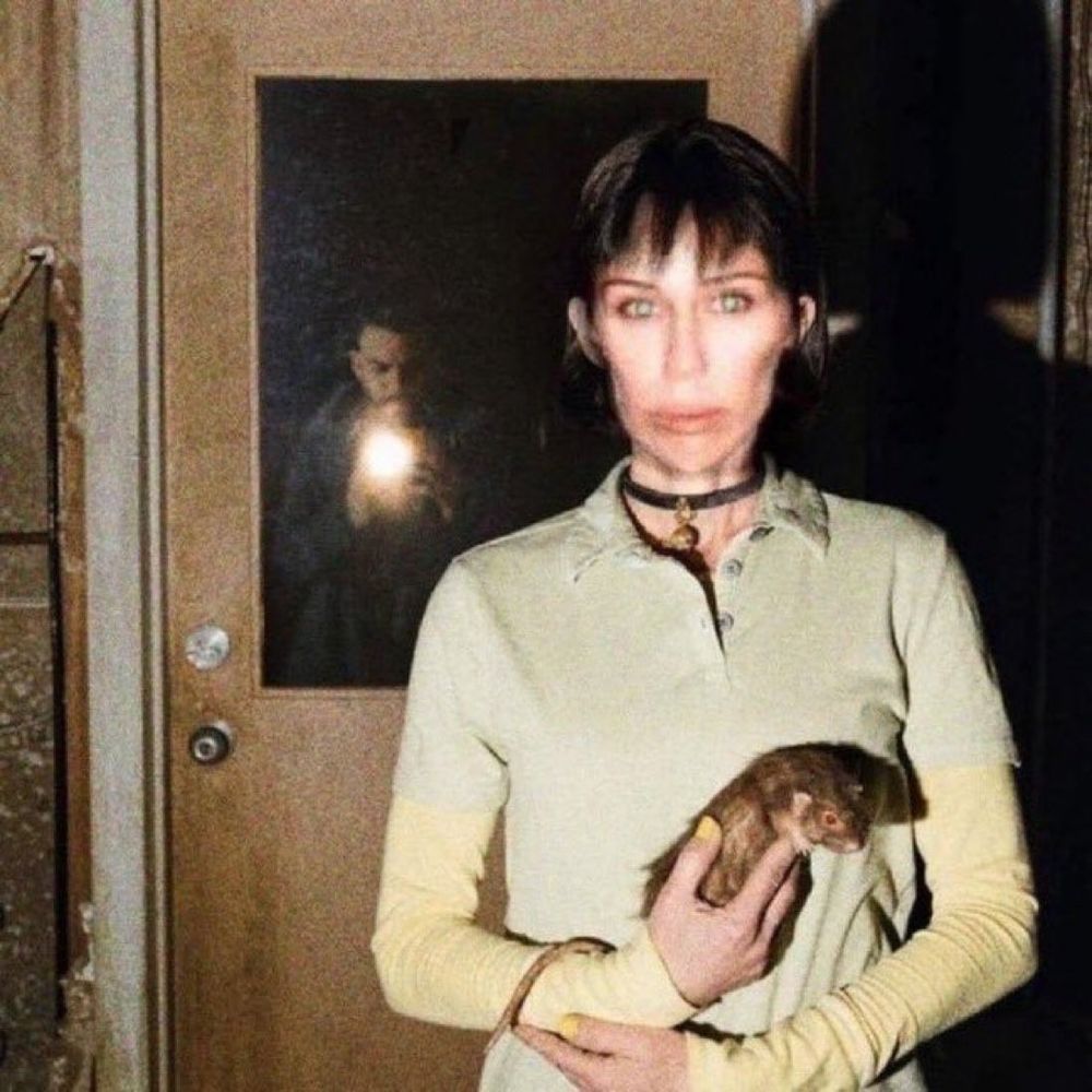 Estático da Miley Cyrus editada num ambiente de terror segurando um rato
