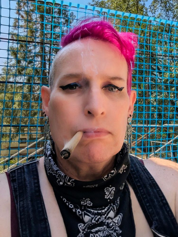 white woman with fuchsia hair smoking a big cone