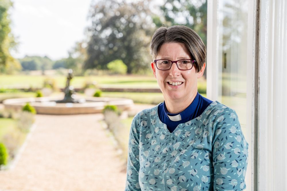 head and shoulders shot of Diane Cooksey who is standing in front of an open doorway looking out into a garden.