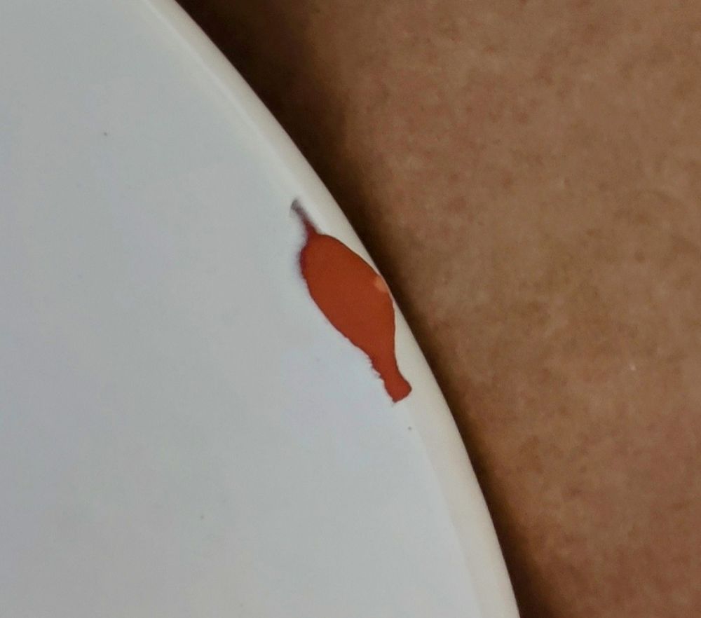 Weiße Kante Blumentopf, ein Stück ist raus gebrochen, man sieht den rotbraunen Ton im inneren