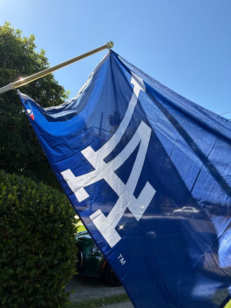 The blue & white flag of the Los Angeles Dodgers on a flagpole. 