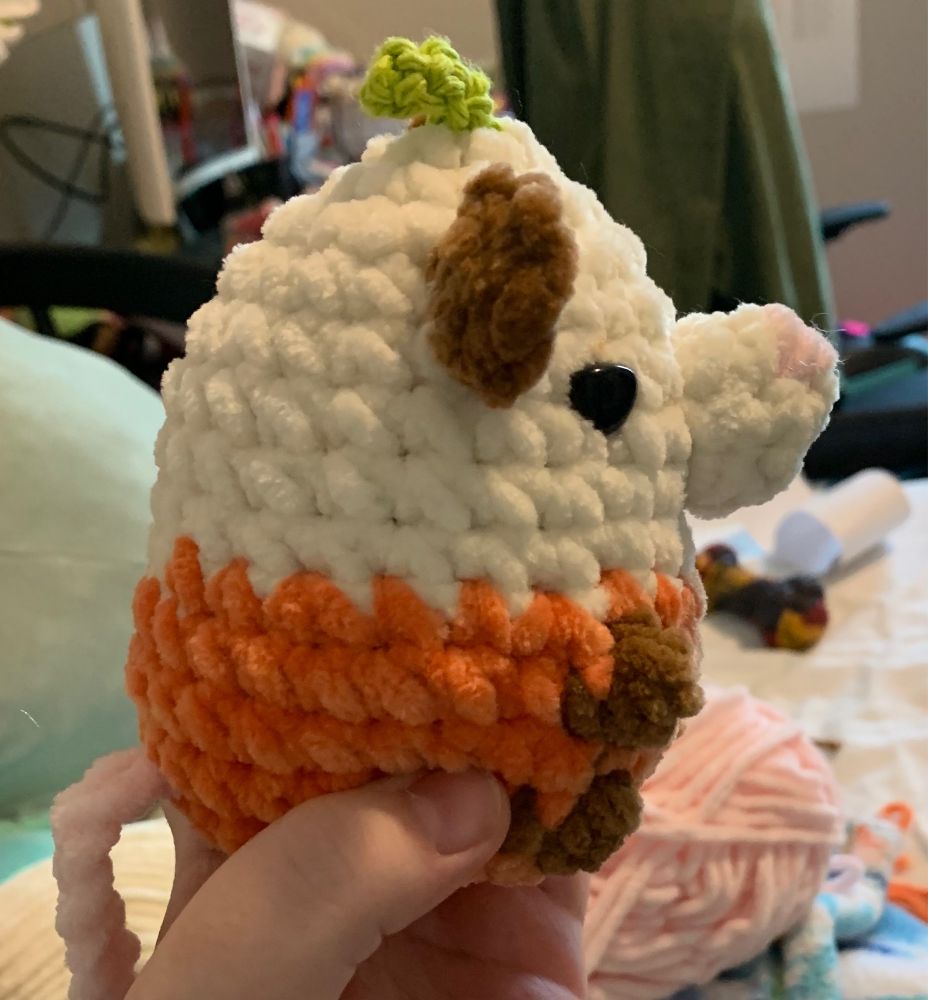 A white brown and orange possom with a small stem and leaf on its head, side view 