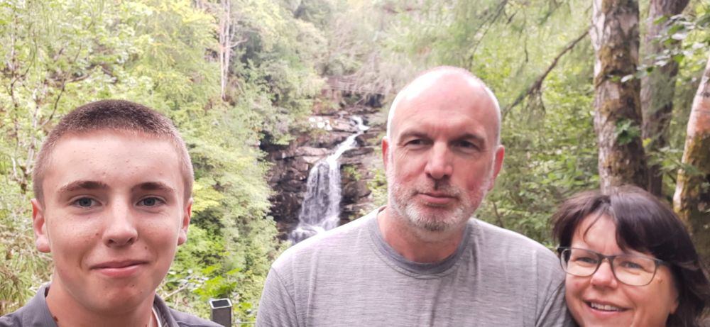 A family selfie with a waterfall in the background.