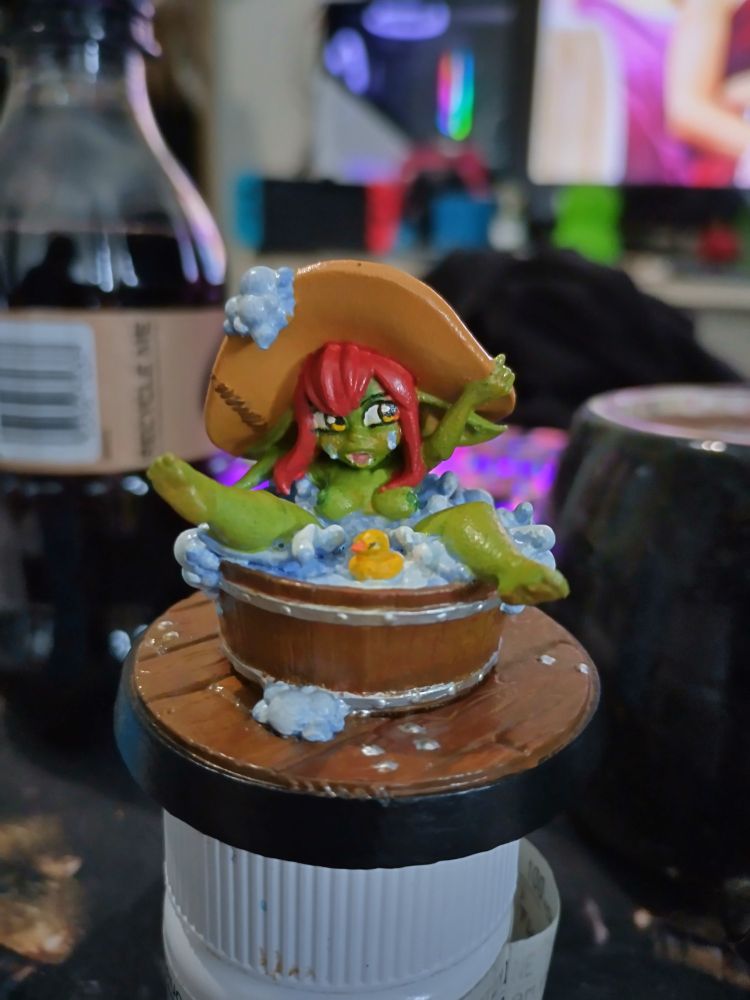Miniature model of a short-stacked goblin naked in a bubble bath wooden tub, with rubber duck and a large hat 