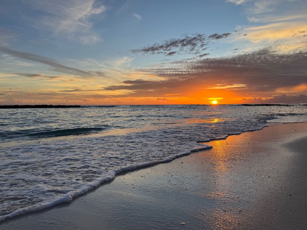 Sun setting over a sandy beach with shallow waves 