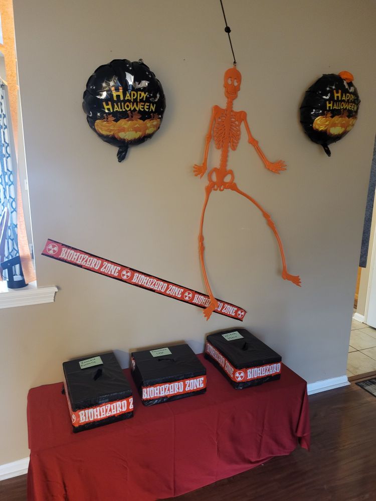 Biohazard Zone: table draped in red with 3 black boxes setting on top. 