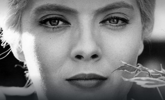 Still from Cleo from 5 to 7: black and white close up of a beautiful young white woman in makeup, looking calm but cynical and preoccupied. A leaf is in front of her