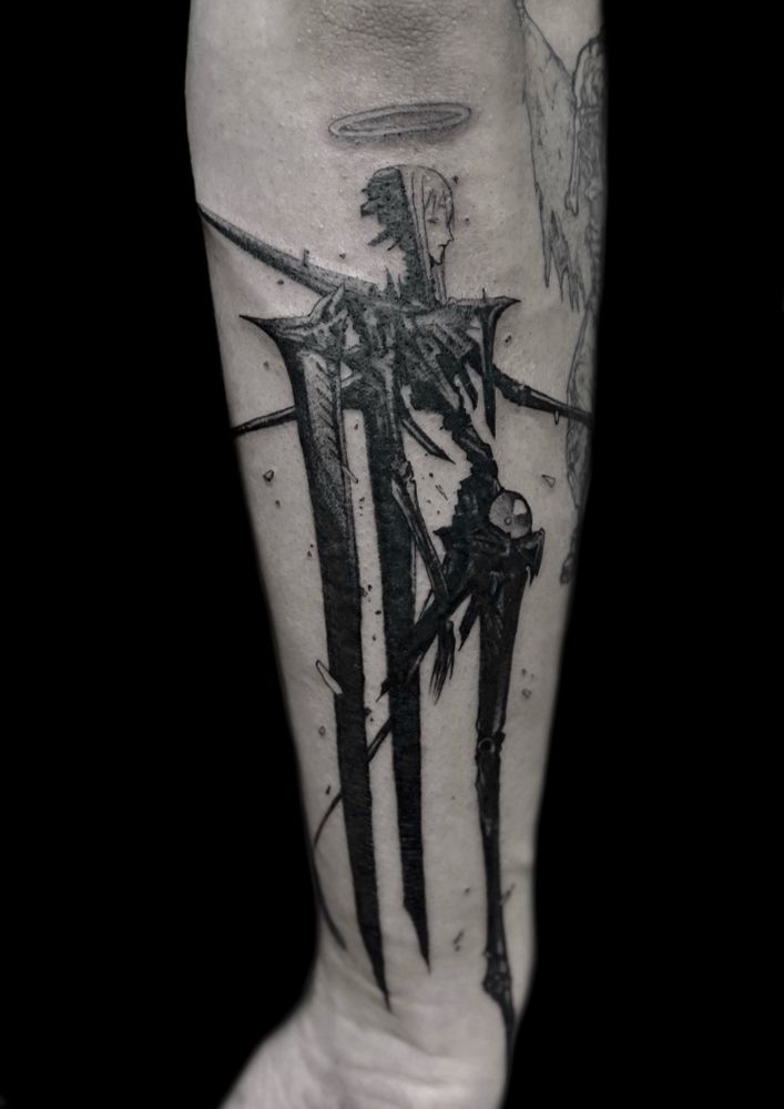 Photo of a tattoo on a man’s the lower arm, black background. Tattoo of a character from the manga Blame by Tsutomu Nihei, representing a dark cyber apocalypse angel humanoid. 