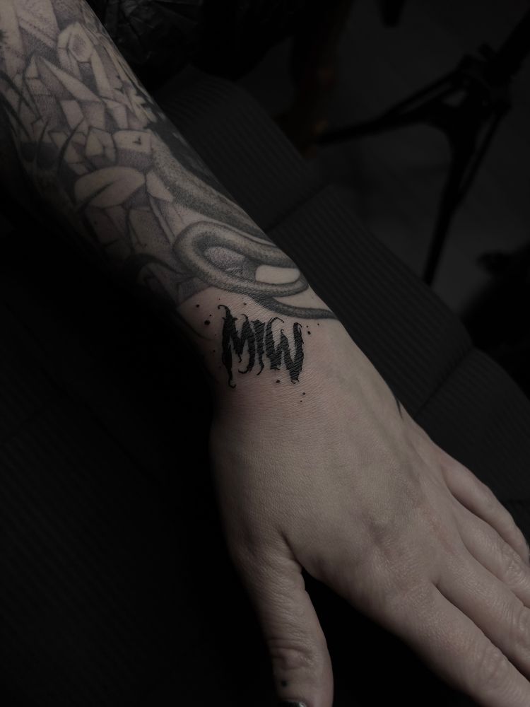 Photo of a female lower arm with a Motionless in white logo tribute tattoo.