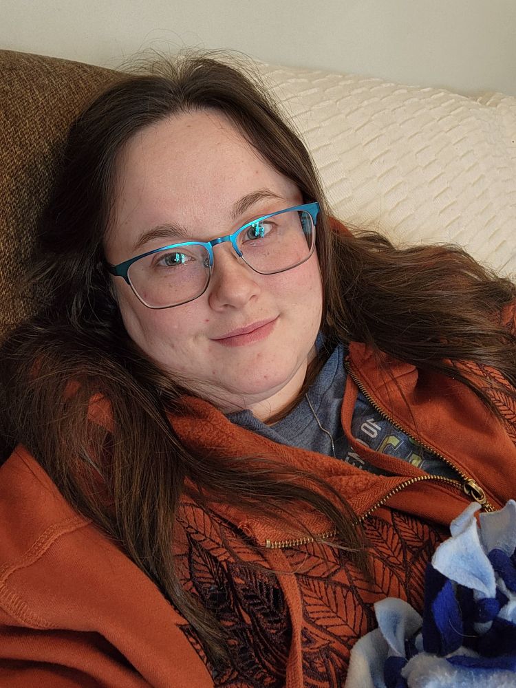 A pale woman with dark hair wearing a burnt orange hoodie based off of Keyleth from Critical Role.