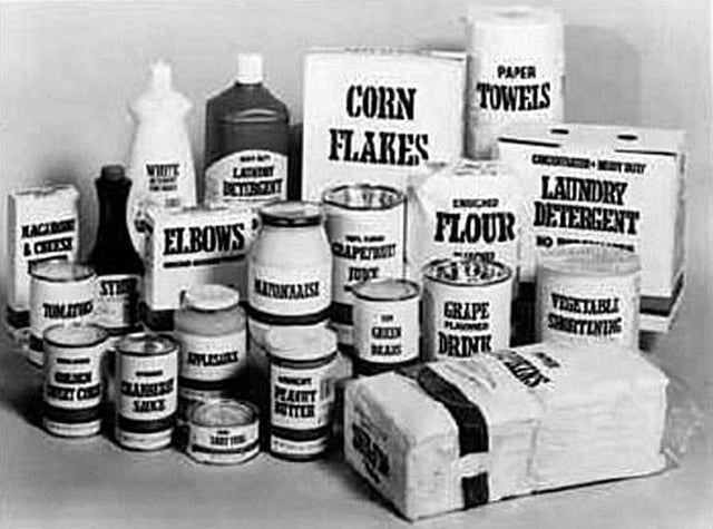 Photo of generic food packaging from the 1980s. White packaging minus any branding information that simply says Corn Flakes, Laundry Detergent, Mayonnaise, etc.. 