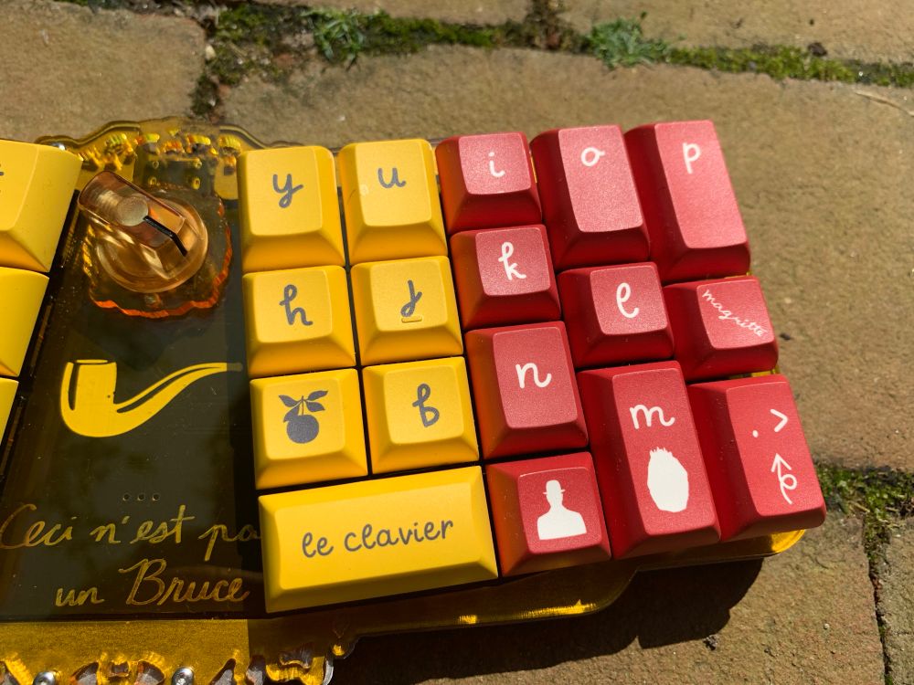 Detail picture of 40% keyboard with keycaps inspired by Rene Magritte in the colours of the Belgian flag  