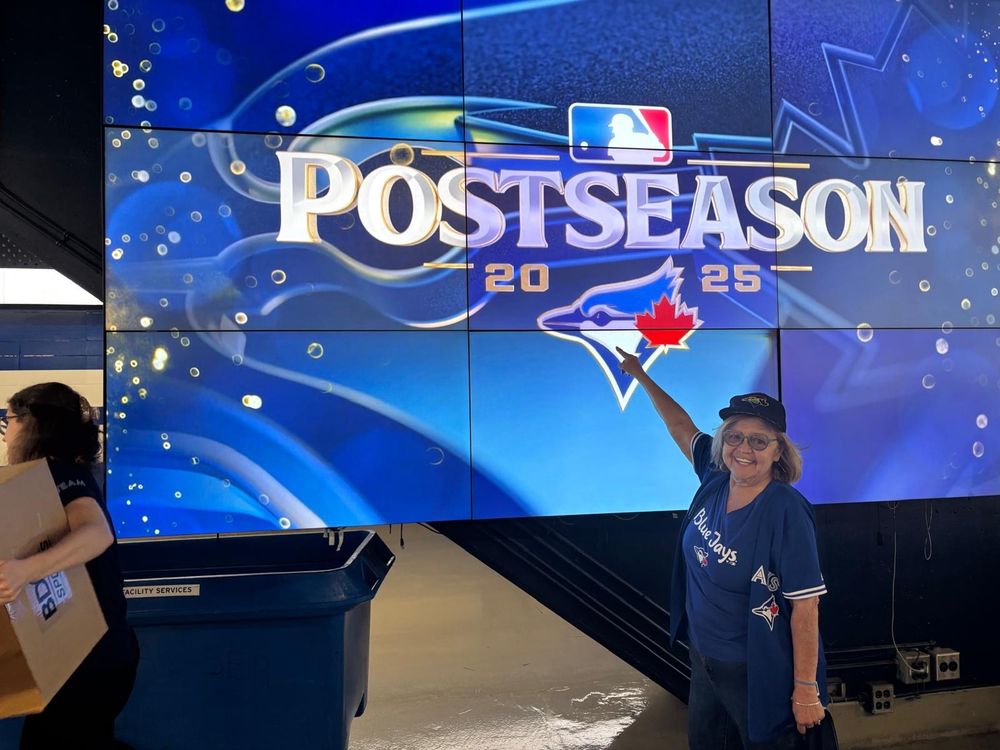 My mom pointing to the Blue Jays logo in a post season 2025 sign at the Rogers Center