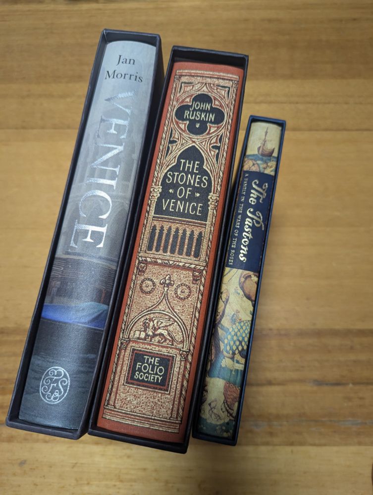 A photo of three hardcover Folio Society volumes in their slip cases: Venice by Jan Morris; The Stones of Venice by John Ruskin; The Pastons, A Family in the Wars of the Roses. 