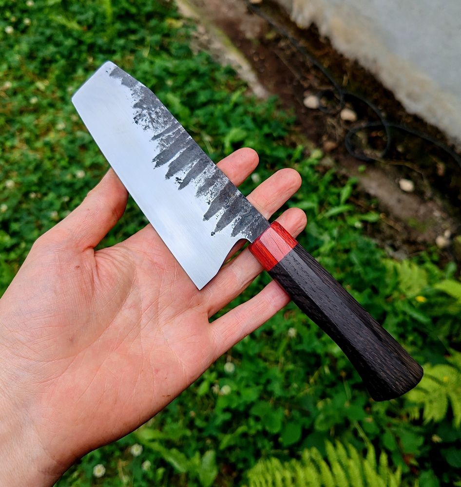 Couteau vu de côté 
Manche rouge et noir 
Lame noire et blanche 