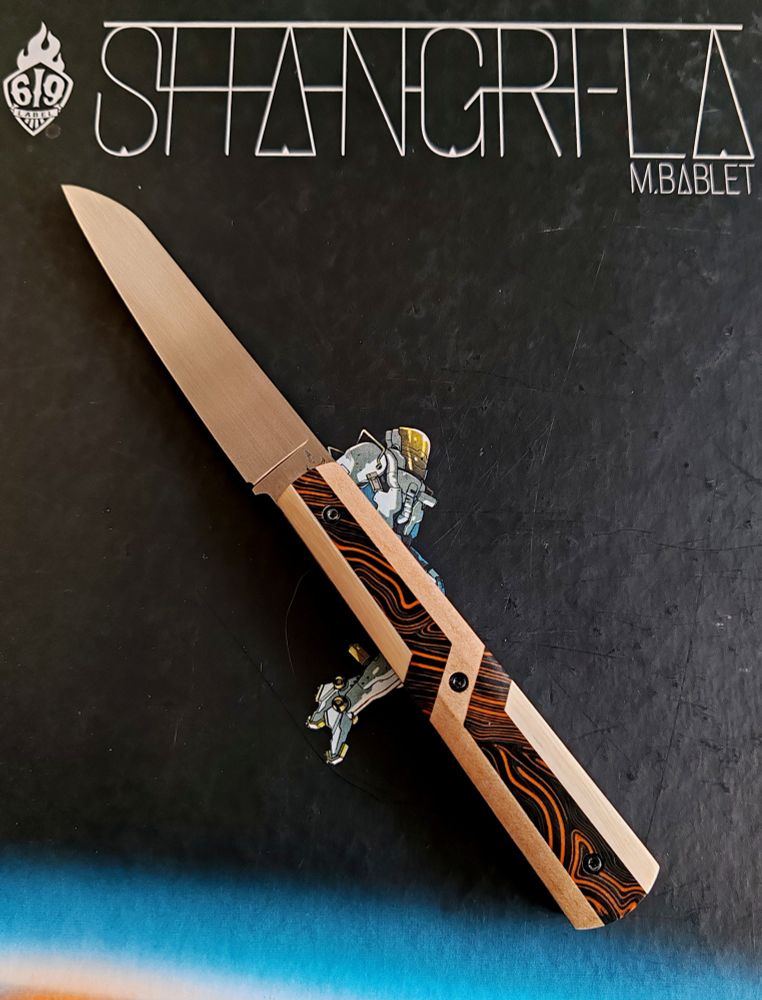 Couteau avec un manche orange et noire avec des formes géométriques crème 
Lame pointé vers le haut à gauche 
En fond l'album shangri-la de m bablet