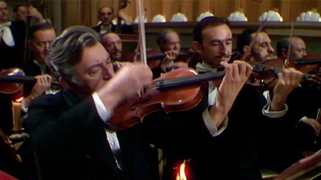 a man playing a violin in front of a large orchestra