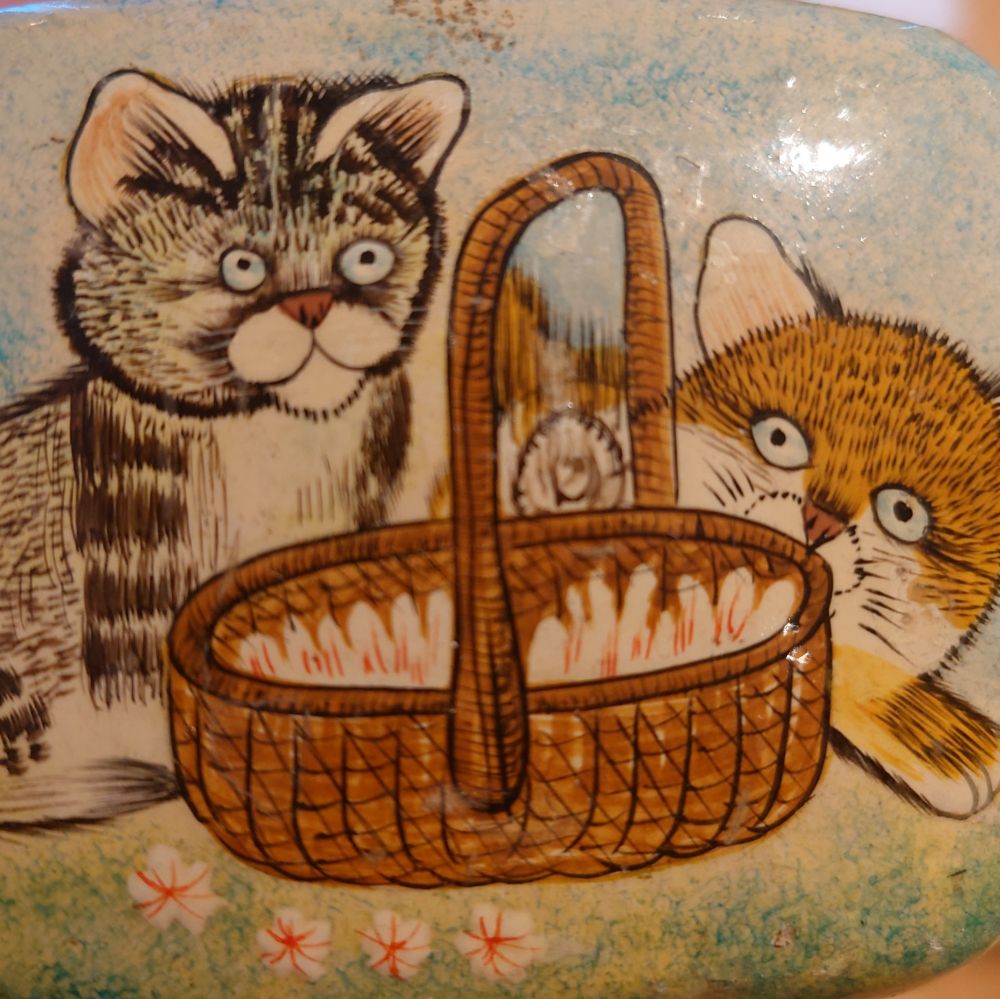 a painting of two completely normal cats by a basket, these cats are incredibly normal, there is nothing not normal about them they are very normal looking cats