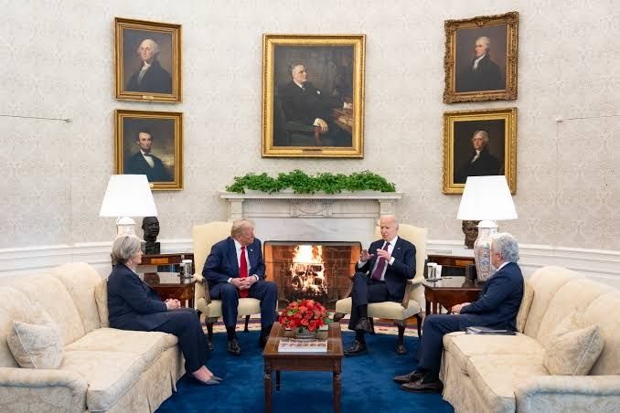 Biden meeting Trump during the handover of the presidency.

The walls of the oval office are a patterned cream and off white with a large gold framed portrait above the white stone mantle piece topped with greenery.

This is the flanked by 2 more goldcframed portraits on each side.