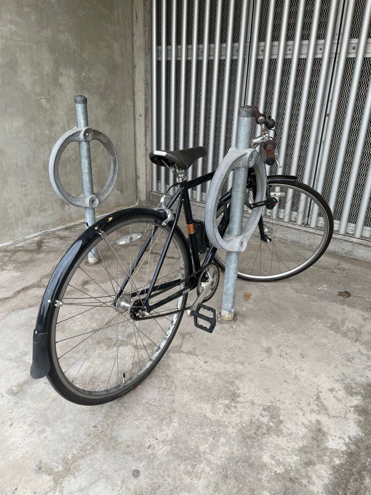 A black commuter bike is locked to a bike ring