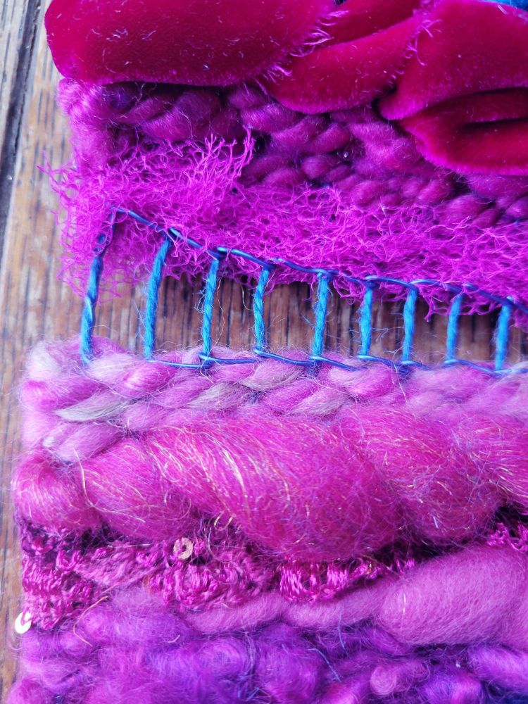 close up of abstract tapestry done in shades of magenta, pink, and blue with multiple textures and densities of fibers