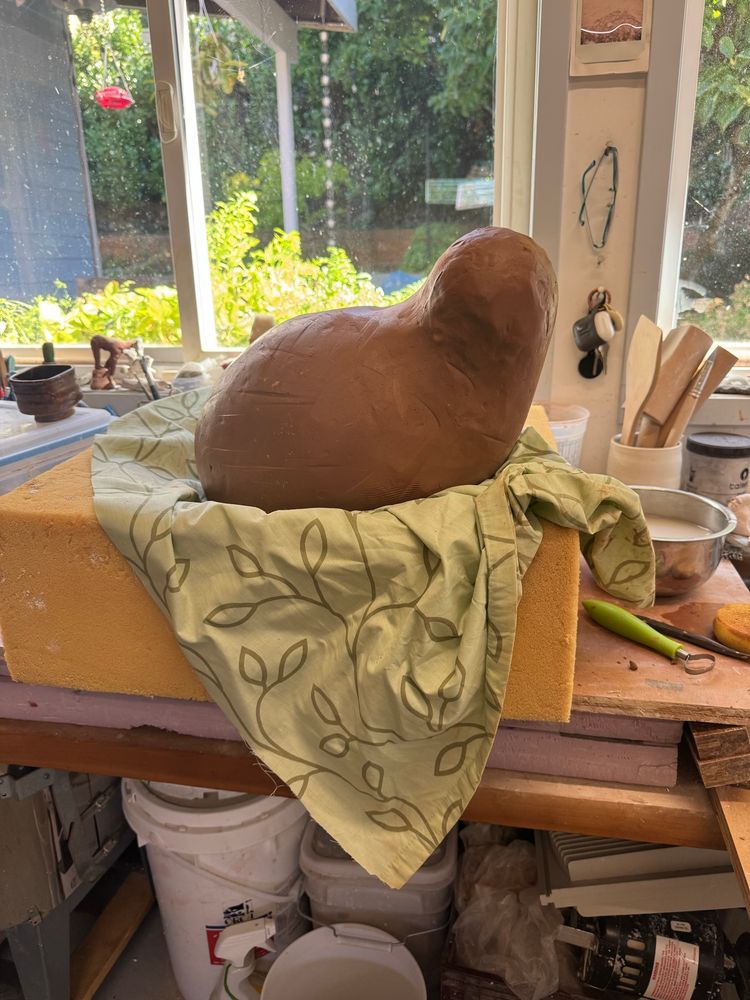 Same beast, before the legs. It’s just a body plus head, but somehow looks inquisitive. It’s on my work bench, but cradled in a big block of foam with a bit of shower curtain protecting the foam. Looks a bit like it’s swaddled in a nest. 