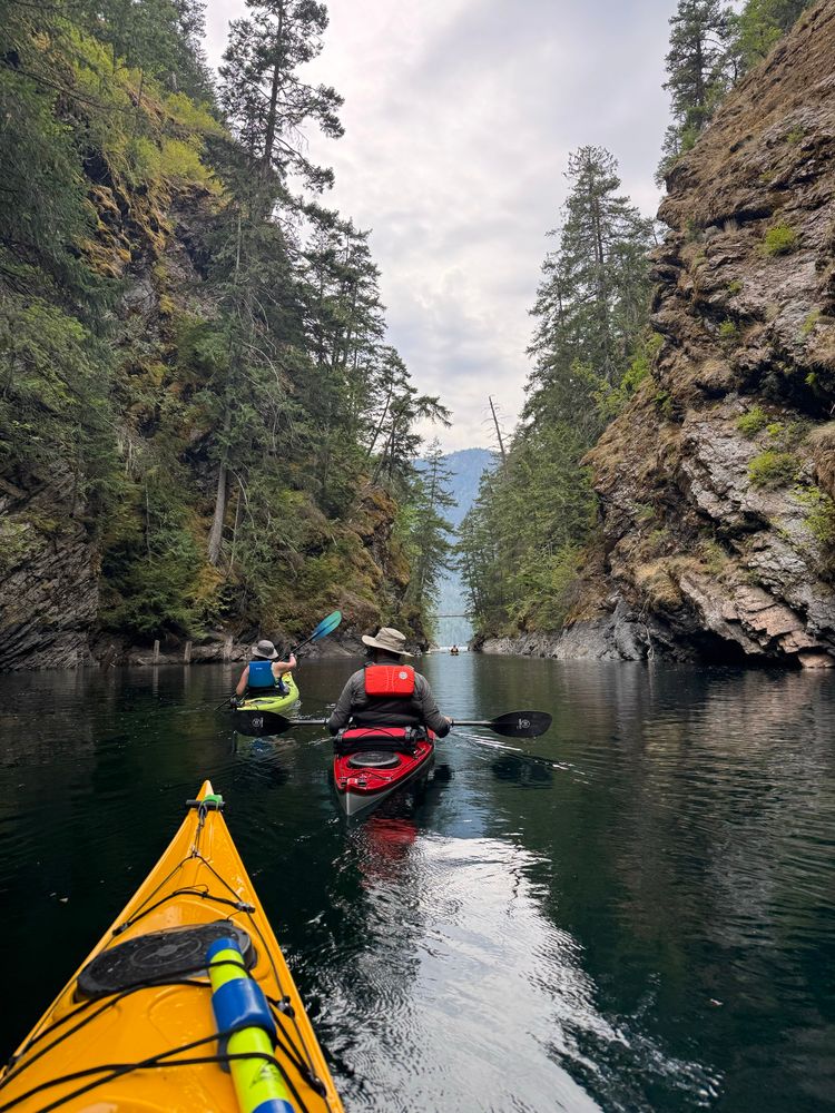 Looking ahead at a group of paddlers in a narrow gorge. You can see the nose of my kayak in the shot