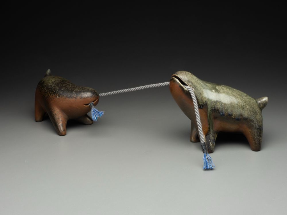 Two wood fired creatures, playing tug of war with a bit of fancy cord. 