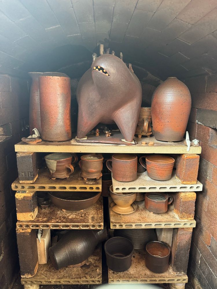 The front most rank of shelves, seen from the inside of the kiln. Many large iron heavy stoneware pots have blushed brick red, which is very unusual. I have a large sculpture on the top shelf, which is looking proud with teeth bared. 