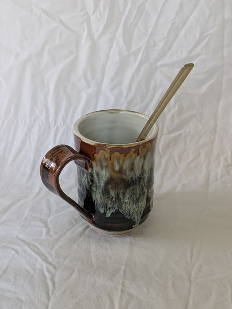 tall mug with white interior and rust/blue/black streaky exterior 