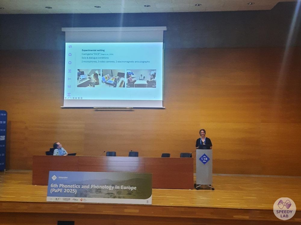 Lena is standing on a stage, next to the sign "6th Phonetics and Phonology in Europe", giving a talk. Behind her, you can see a slide on experimental methods.