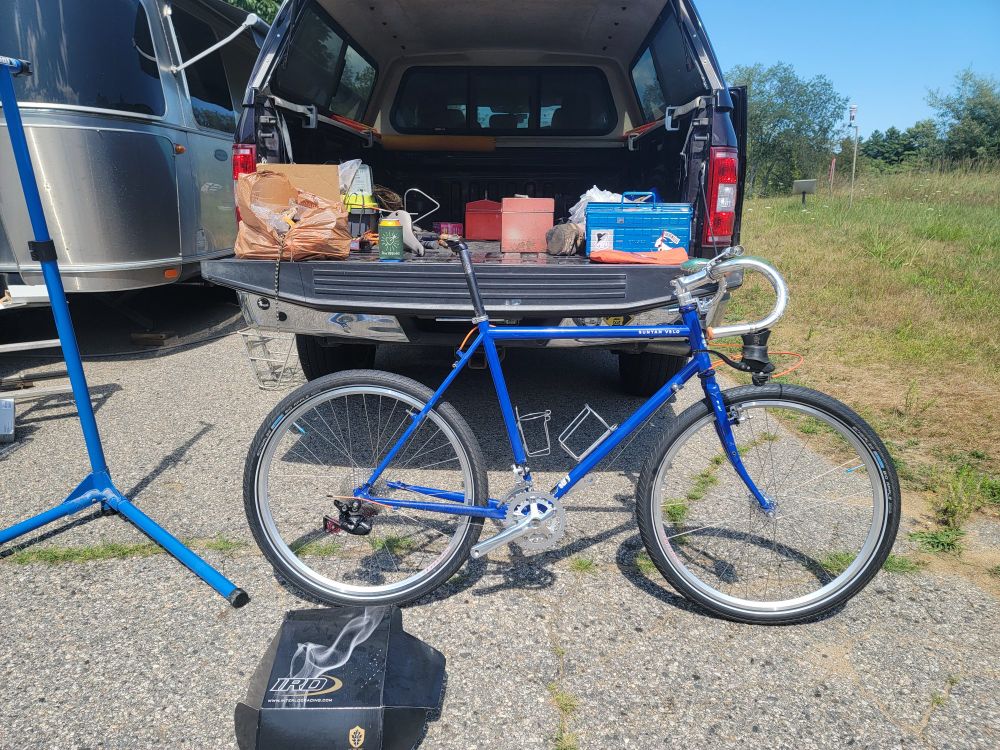 Partially built-up blue bike leaning against an open tailgate.