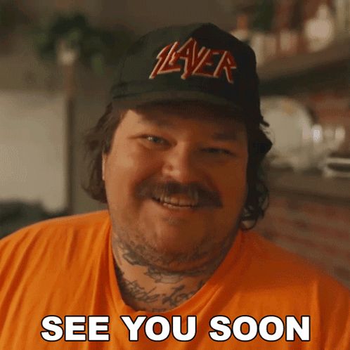a man wearing a slayer hat is smiling and says see you soon