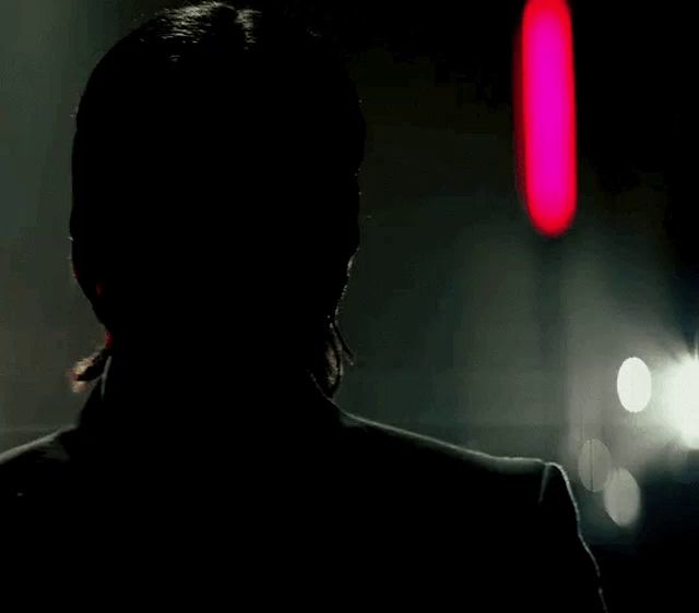 a close up of a man 's face in the dark with a red light in the background