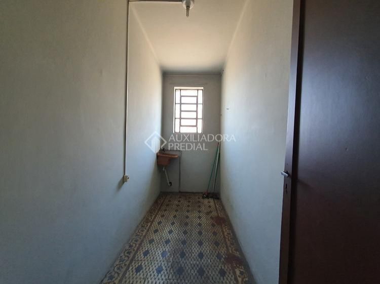 área de serviço que parece um grande corredor com uma janelinha minúscula e um tanque lá no fundo. piso semi destruído de ladrilho hidráulico (o piso é adorável, seria maravilhoso se desse pra restaurar)