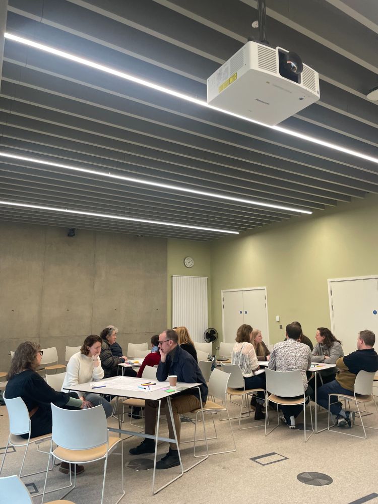 People gathered around three tables having discussions.
