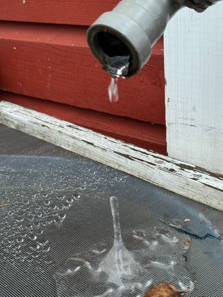 Vesipisara putoaa putken päästä. Alla on ritilä, jonka päälle on jäätynyt tipoista korkeuksia kohti kurotteleva jääpuikko.